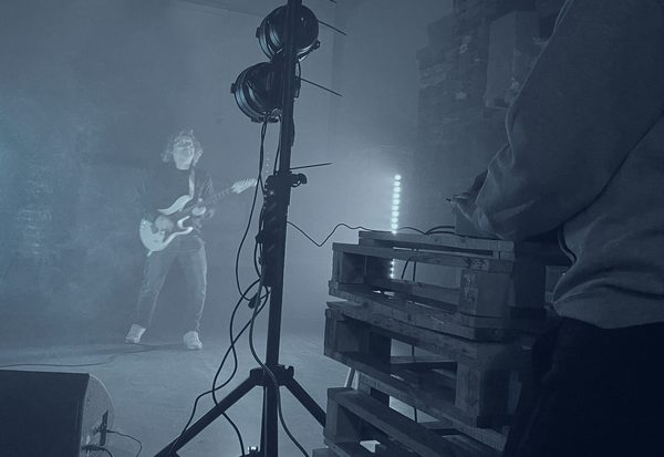 Chitarrista sul palco avvolto dalla nebbia e dalle luci